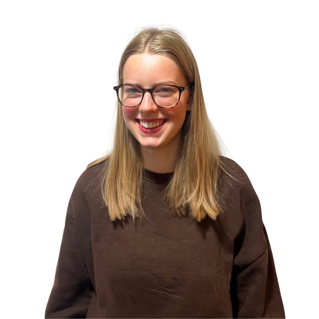 Our FYPO, Vicky, smiles at the camera. She has long, chestnut brown hair and is wearing black framed glasses and a bright red top with white flowers on it.